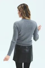 Polera tejida gris de manga larga y cuello alto, corte al cuerpo y largo a la segunda cadera.