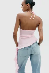 Top negro de cuello halter con lazada, escote recto y hombros descubiertos. Presenta un volante asimétrico en el lateral.