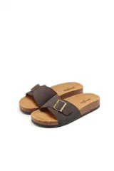 Sandalias tostadas estilo Birkenstock con una tira ancha cruzada en el empeine, hebilla metálica dorada decorativa y suela de corcho con base de goma negra.