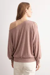 Blusa rosada de manga dolman larga, con escote asimétrico estilo hombro caído y detalle de abertura en la manga.