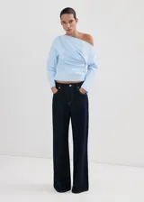 Blusa de algodón celeste con diseño asimétrico de un solo hombro, detalles fruncidos y manga larga.