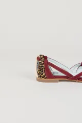 Bailarinas planas confeccionadas artesanalmente con una combinación de ante, napa y tejido estampado. Presentan un diseño geométrico con tiras entrelazadas en la parte delantera que combinan tonos vino tinto, beige, naranja teja, marrón y estampado de leopardo. Cuentan con un ligero tacón y plantilla fija de piel.