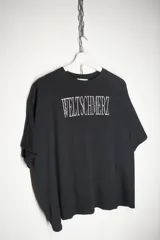 Remera negra de corte cropped con estampa frontal en color blanco que presenta la palabra Weltschmerz con un diseño tipográfico distorsionado.