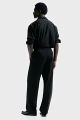 Pantalón de corte relajado con cintura elástica y cordón de ajuste. Presenta pliegues frontales y traseros, bolsillos laterales discretos y un bolsillo trasero insertado.