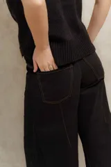 Pantalón de pierna ancha con tiro medio, confeccionado en brin de algodón con spandex. Presenta costuras a contratono que resaltan su diseño y bolsillos laterales.