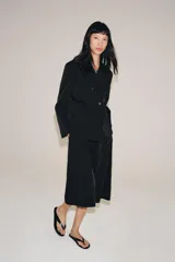 Blazer cruzado Zara de color negro, con cuello de solapa, manga larga y bolsillos laterales ocultos en la costura. Cuenta con cierre frontal de botones.