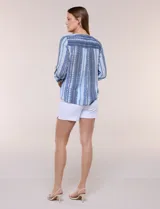 Blusa de gasa Zac & Rachel con estampado de rayas verticales en tonos rosados, amarillos y blancos. Presenta escote en V con cuello mao, cierre frontal con botones, un bolsillo aplicado en el pecho, mangas largas con presilla para regular el largo y detalle de nudo en el dobladillo inferior.