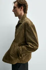 Sobrecamisa relaxed fit de piel con acabado en ante de color verde militar, con cuello solapa, manga larga con puño abotonado, bolsillos de vivo en la cadera y cierre frontal con botones.
