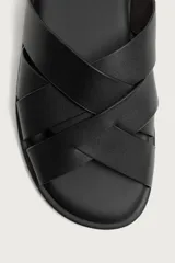 Sandalia plana de hombre confeccionada en piel color negro, con diseño de tiras cruzadas y entrelazadas en el empeine.