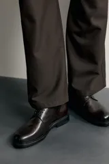 Zapato de cordones tipo blucher color marrón oscuro, confeccionado en piel con horma redonda y suela con ligero tacón.