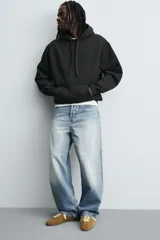 Sudadera tipo hoodie de corte relajado, confeccionada en tejido de algodón con interior cepillado. Presenta capucha con cordones ajustables, bolsillo frontal tipo canguro y terminaciones en rib en puños y ruedo.