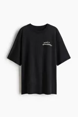 Remera oversized de algodón color negro, con cuello redondo acanalado, mangas cortas y diseño estampado en el pecho.