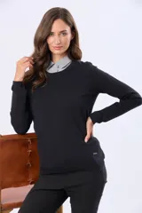 Buzo tejido en hilo de algodón color beige, con cuello redondo y manga larga. Presenta un corte clásico y un pequeño detalle metálico en la parte inferior izquierda.