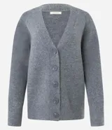 Cardigan de punto color beige con escote en V, cierre frontal con botones grandes y mangas largas con puños acanalados. Presenta un corte recto y estructurado.