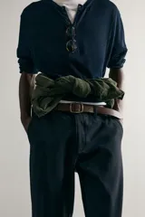 Pantalón chino negro slim fit de corte recto, con bolsillos frontales, trabillas para cinturón y cierre frontal con cremallera y botón.