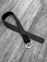 Cinto negro de cuero sintético con tachas plateadas y hebilla metálica plateada.
