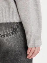 Sweater de tejido de punto color gris claro, con cuello redondo, mangas largas y terminaciones acanaladas en puños y ruedo.