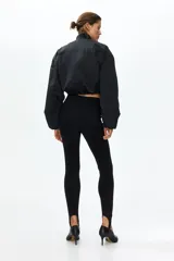 Leggings negros de tiro alto en punto elástico, con pliegues frontales pespunteados y estribos en los tobillos.