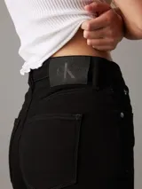 Pantalón de jean negro, de tiro alto, corte ajustado en la pierna y acampanado en el tobillo.