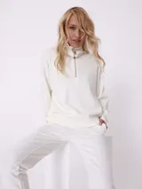 Sweater blanco de tejido de punto, con cuello alto con cierre metálico y mangas largas.