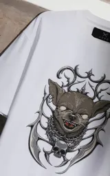 Remera blanca de corte holgado con estampa frontal de un perro chihuahua con diseño gótico, rodeado de elementos ornamentales y una calavera.