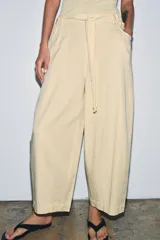 Pantalón de tiro medio confeccionado en mezcla de lyocell, con diseño de pierna ancha y tejido en espiga. Cuenta con cintura elástica ajustable con cordones y bolsillos laterales.