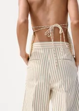 Pantalón de vestir de tiro medio con diseño de rayas verticales en tono beige y crudo. Presenta pernera recta y holgada, con pinzas delanteras y bolsillos laterales.