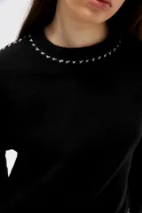 Sweater negro de corte holgado con cuello redondo a la base y detalle de costuras decorativas en contraste a lo largo de las mangas y el cuello.