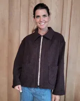 Chaqueta de textura bouclé en color bordó, con corte oversize, cuello camisero, cierre frontal y bolsillos laterales.