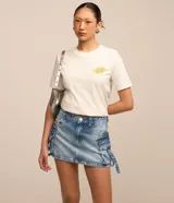 Pollera corta de jean azul con efecto deslavado, tiro medio, trabillas en la cintura y bolsillos cargo laterales con tiras y hebillas decorativas.
