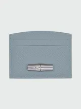 Tarjetero Longchamp modelo Roseau de cuero color celeste con tres ranuras para tarjetas y cierre con broche metálico plateado en forma de bambú.