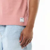 Camiseta de cuello redondo y manga corta color rosado, con textura en nido de abeja y pequeña etiqueta decorativa en el dobladillo.