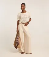 Pantalón pantalona de viscosa color crudo, con trabillas en la cintura, pliegues delanteros y bolsillos cargo utilitarios en los laterales.