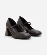 Zapato estilo Mary Jane de poliuretano color marrón oscuro, con punta redondeada, tira con hebilla ajustable sobre el empeine y taco bloque de altura media con acabado símil madera.