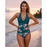 Malla entera de color verde oscuro, combinada con un diseño floreado en la parte inferior. Presenta escote halter cruzado y fruncidos en la zona del abdomen.