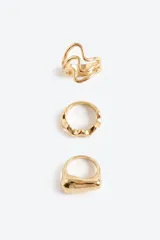 Set de tres anillos de diseño orgánico y voluminoso en tono dorado. Cada anillo presenta una forma distinta: uno con líneas onduladas, otro con relieve irregular y un tercero de superficie lisa y redondeada.