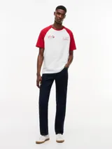 Remera de cuello redondo con diseño de mangas raglán en color rojo y cuerpo en color blanco. Presenta un estampado gráfico en el pecho con banderas de carreras y el logo de la colaboración Tommy Hilfiger x Cadillac Formula 1 Team.