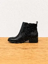 Botinetas de cuero azul marino, con diseño de doble cierre lateral y talón con textura en relieve tipo cocodrilo. Cuentan con taco bajo y suela de goma.