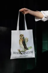 Bolso tipo tote bag de color blanco, con estampado de una lechuza y la leyenda 'DIARIO SILVESTRE MANOS DEL URUGUAY' en la parte inferior.