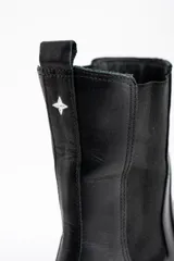 Bota tipo Chelsea de cuero negro, con paneles elásticos laterales y suela de goma con plataforma baja.