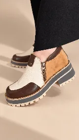 Zapatos de cuero con diseño tricolor en tonos marrón, tostado y marfil, con plataforma y suela dentada. Cuenta con cierre lateral y costuras decorativas.