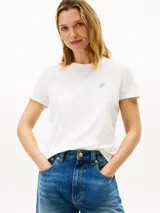 Remera de manga corta color blanco con cuello redondo y corte regular, confeccionada en algodón y elastano. Presenta el logo script de Tommy Hilfiger bordado en azul claro en el pecho.