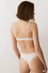 Soutien push-up color beige de punto acanalado, con copas acolchadas, aros, breteles ajustables y cierre de corchetes en la espalda. Presenta detalles de encaje en el borde superior de las copas y un pequeño lazo en el centro.