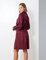 Vestido corto color borgoña con estampado geométrico, de gasa laminada con cuello alto entrelazado, manga larga raglán, cintura elastizada y espalda con abertura ojal y botones.