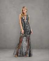 Vestido largo de fiesta con diseño de cebra, bordado íntegramente con lentejuelas plateadas sobre base negra. Presenta un escote profundo con paneles de tul transparente y falda con transparencias.