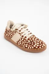 Zapatilla de cuero con textura de pelo y estampado animal print de puntos, con detalles en cuero liso color crema en los laterales y talón, y suela de goma color caramelo.