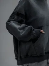 Hoodie oversize de corte crop en color gris oscuro, confeccionado en algodón rústico. Presenta un diseño con costuras expuestas, efecto de desgaste y detalles de roturas en los bordes, incluyendo puños y ruedo.