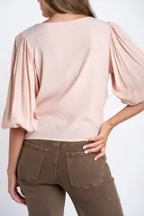 Blusa color rosa pálido, de manga larga abullonada con puño elástico y escote redondo.