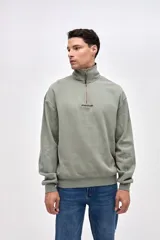 Buzo de felpa con friza, color negro, con cuello alto y cierre frontal parcial. Presenta bordado de la marca en el pecho y un calce relajado.