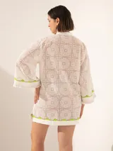 Túnica corta blanca de encaje con bordes y palmeras bordadas en verde neón.